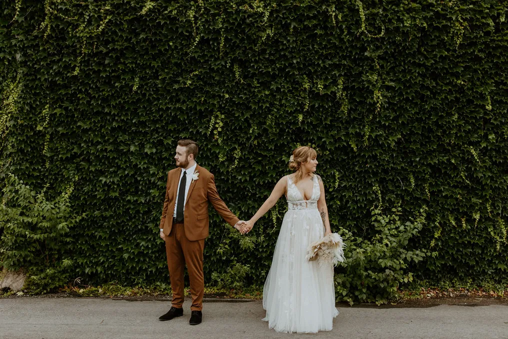 Couple holding hands by the ivy wall at Brickyard on Main