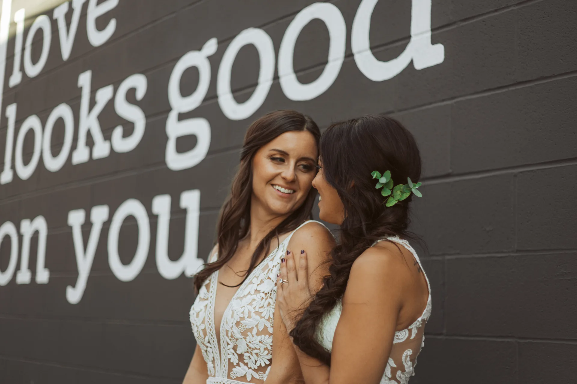 Brides by the 'love looks good on you' mural at Brickyard on Main