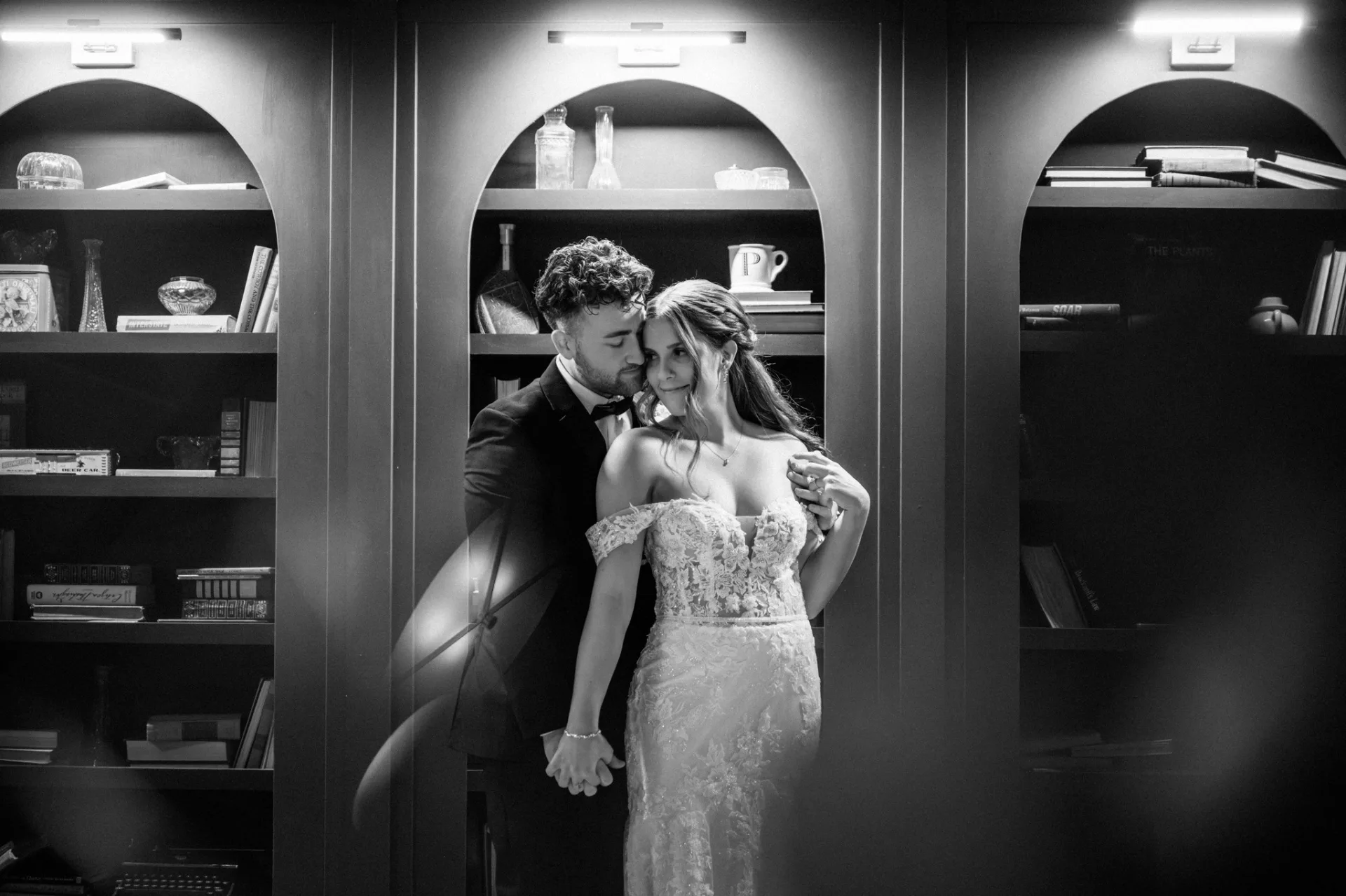 Bride and groom in front of the arched library shelves at Urban501